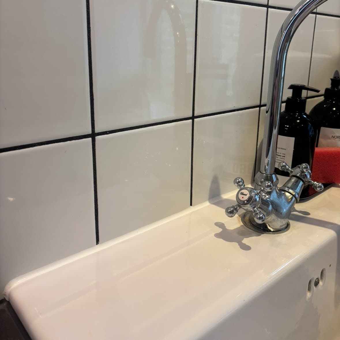 Ny silikonefuge trukket i overgangen mellem fliser i et badeværelse